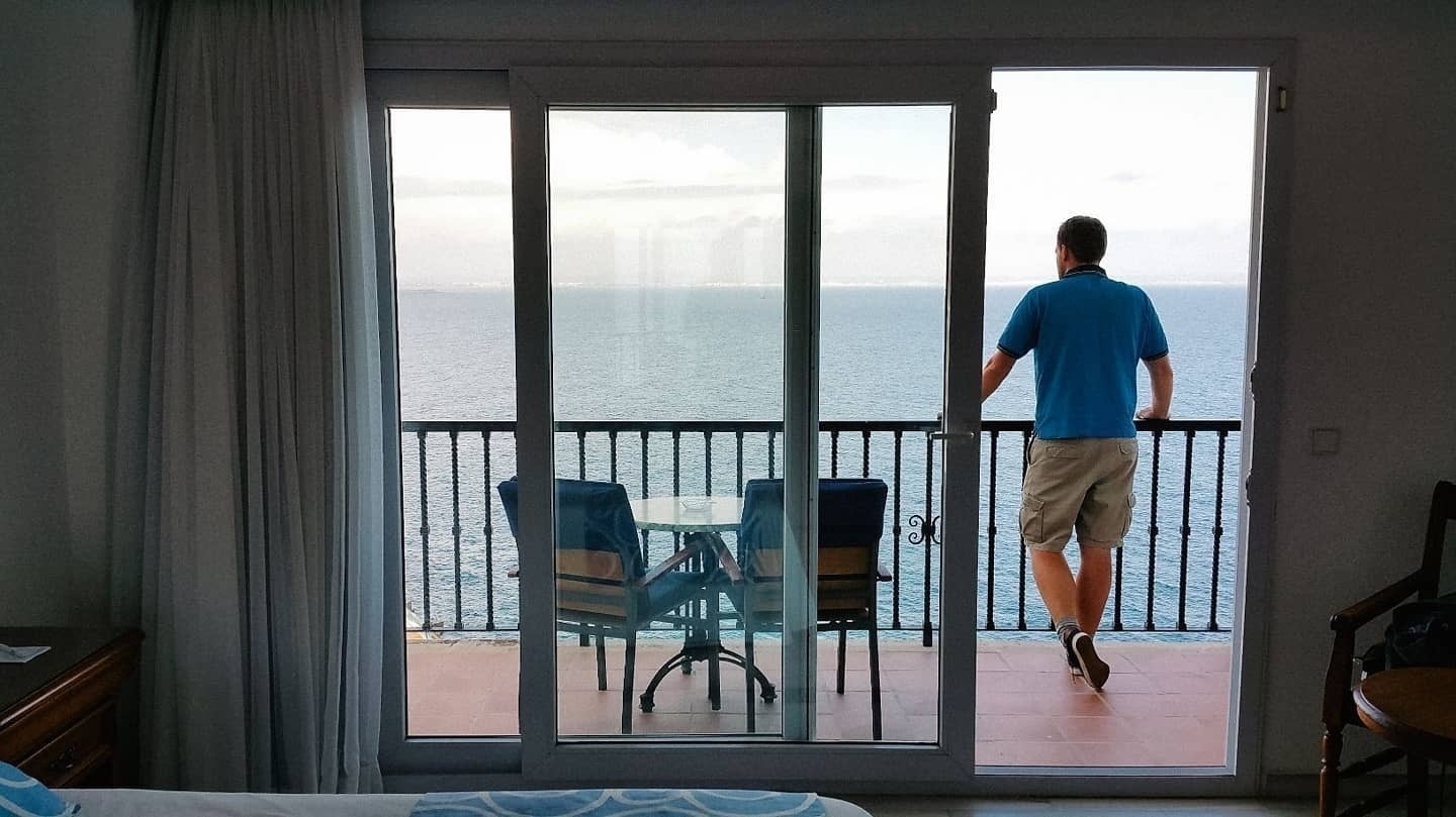 Auto-generated description: A person is standing on a balcony overlooking the ocean.