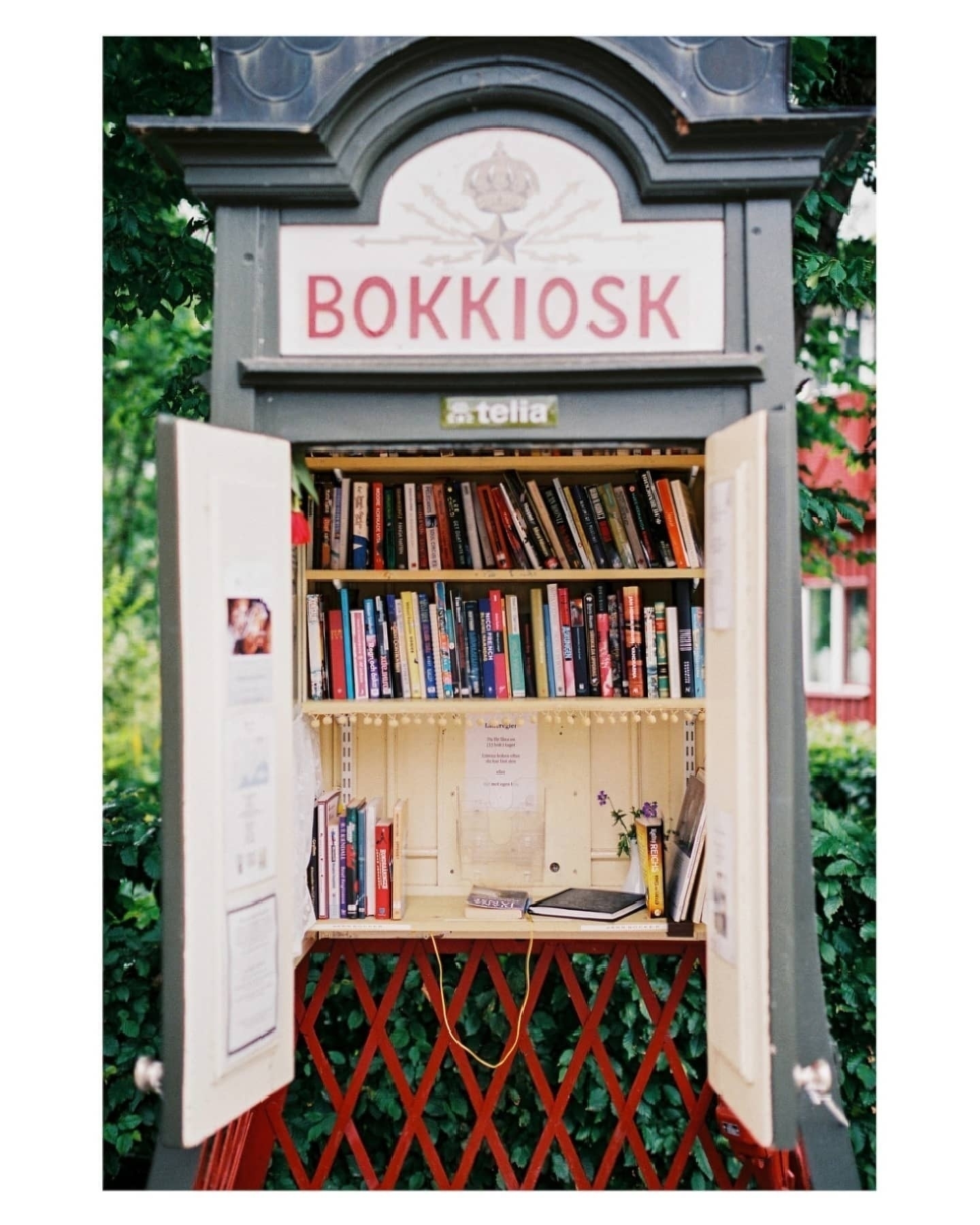 A converted phone booth serves as a small public library filled with books and labeled Bokkiosk.