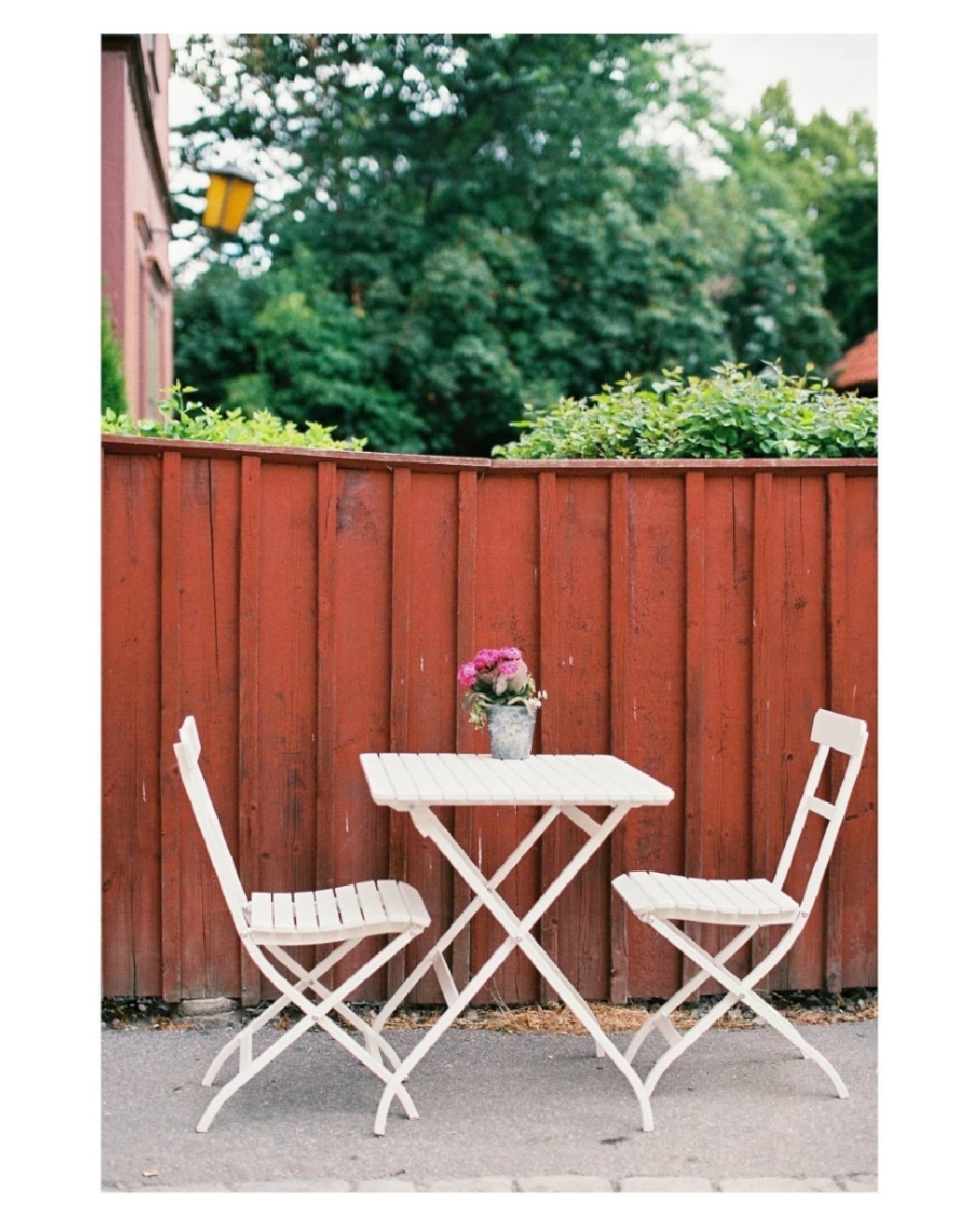 A small outdoor table with two white chairs