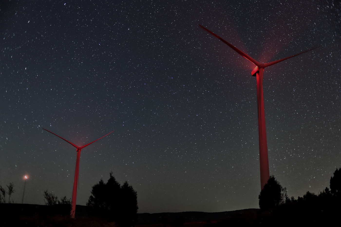 Two wind turbines under a starry night sky.