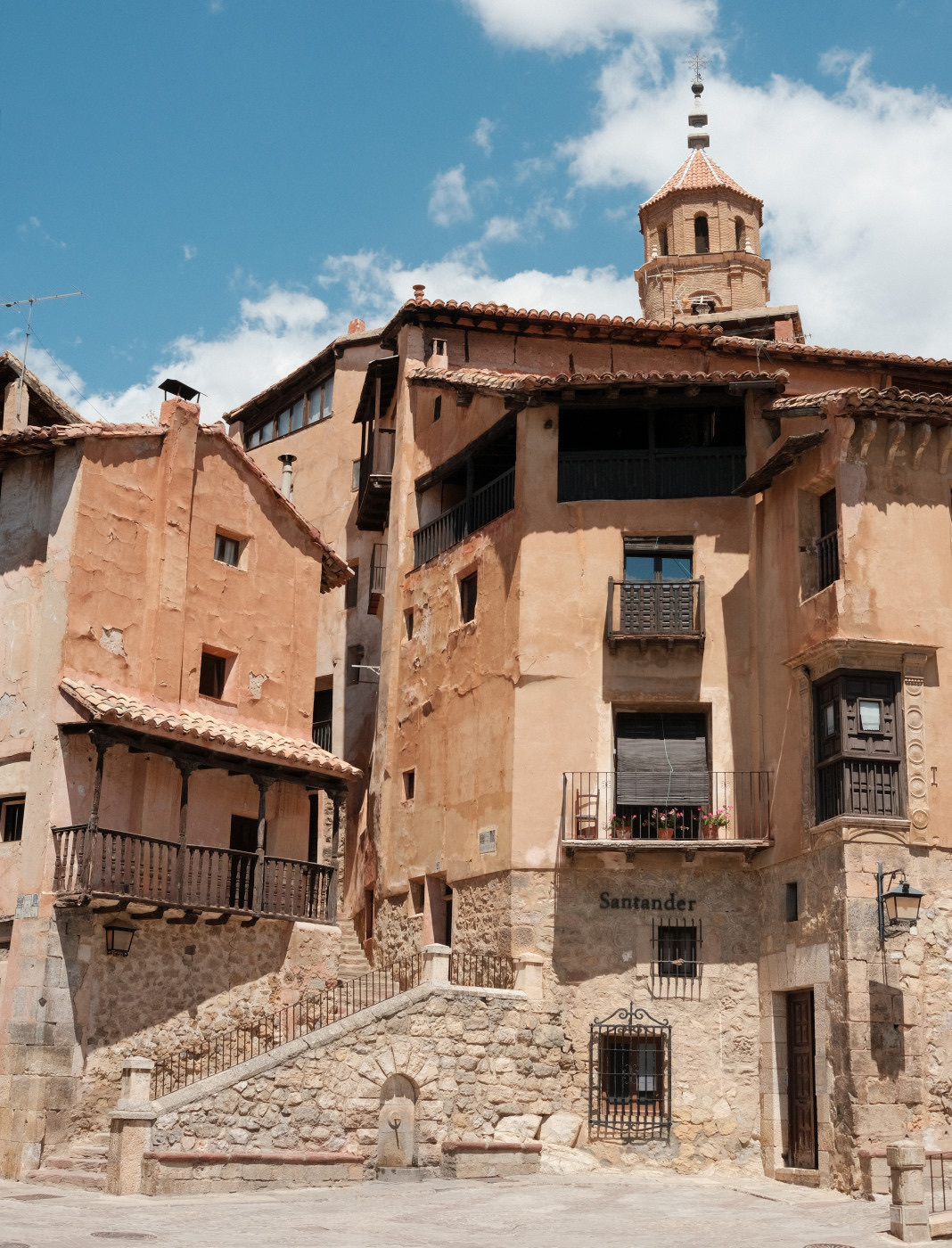 Auto-generated description: A rustic, historic building stands under a bright sky, showcasing warm-toned stonework and a small bell tower.