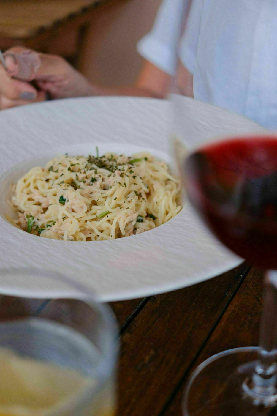 A plate of good pasta alongside glasses of good red wine.